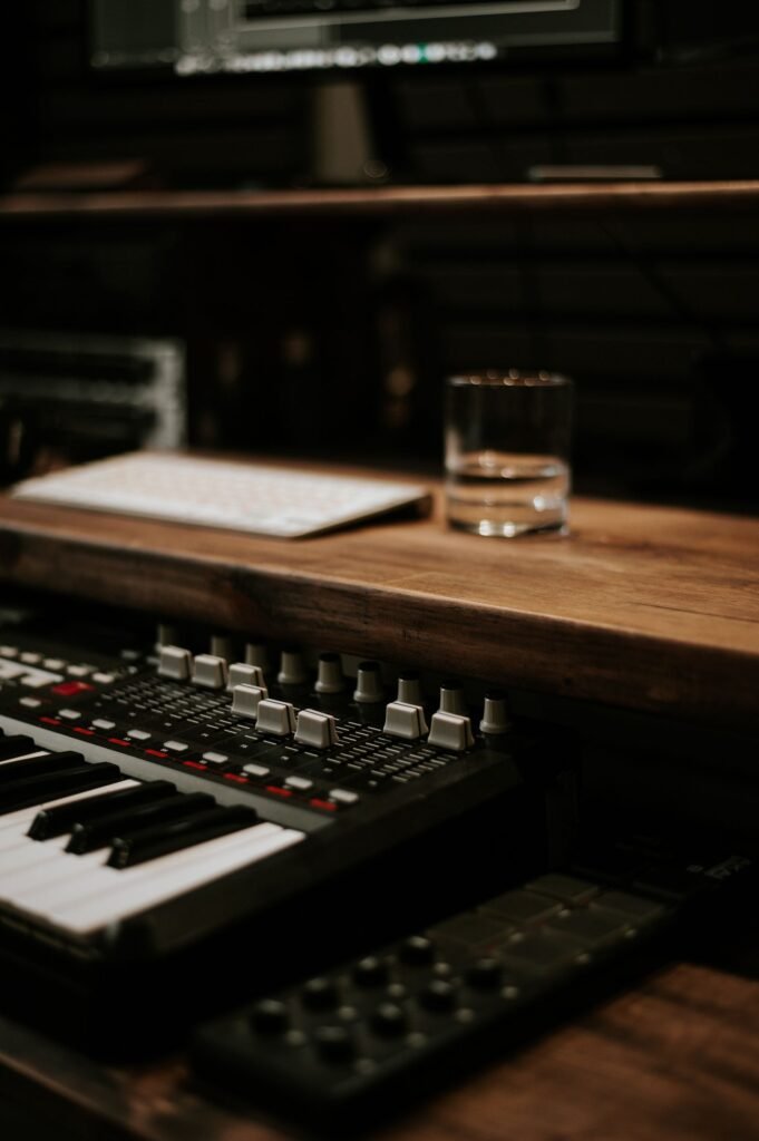 Synthesizer keyboard and computer on a desk in a dimly lit home music studio