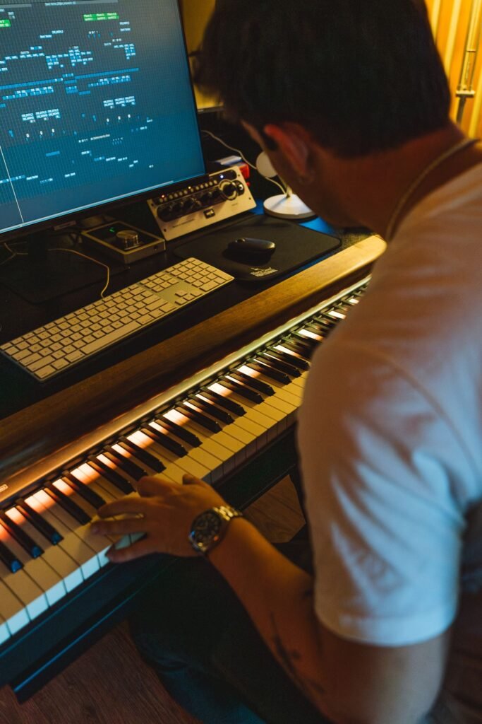 Music producer playing a keyboard in front of a computer screen in a home studio