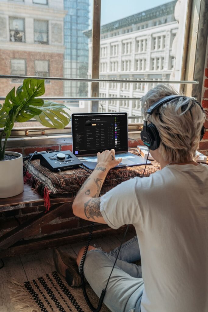 Producer wearing headphones working on a track on a laptop